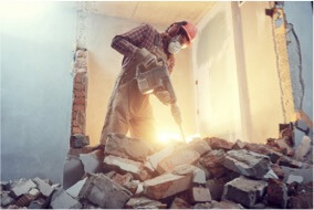 a worker breaking down the brick wall