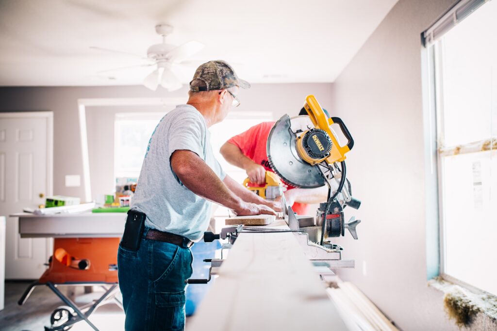 Two men using a drop saw while doing home renovations