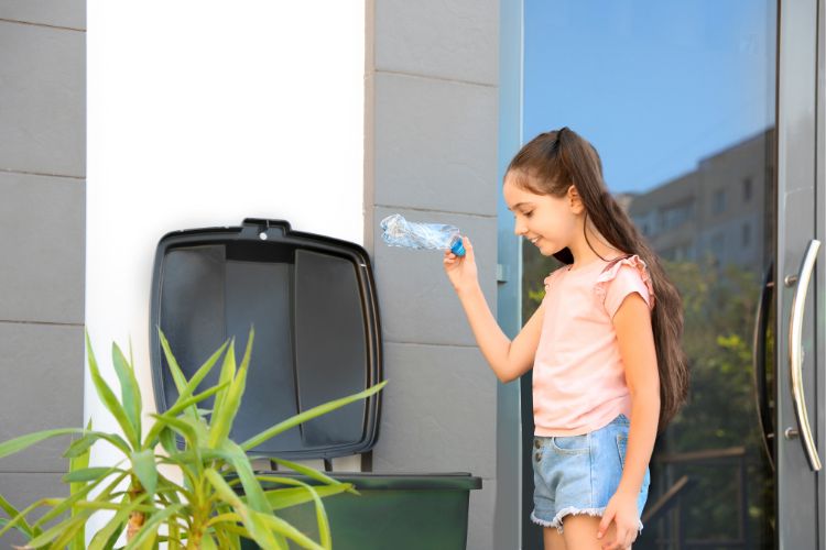 girl putting a plastic bottle in a recycling bin